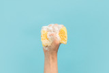 cropped view of hand holding washing sponge with foam, isolated on blue