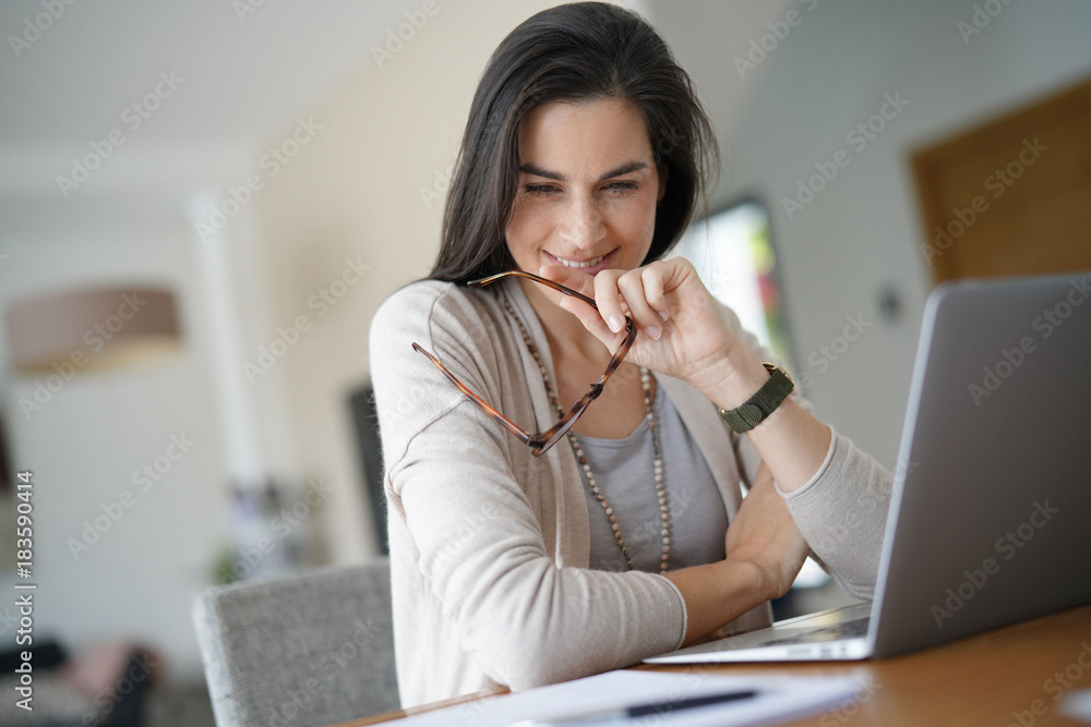 Cheerful woman working on laptop at home-office Cheerful woman working on laptop at home-office