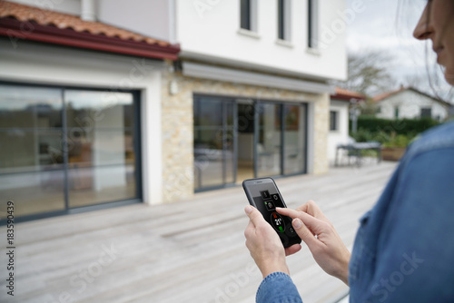 Photos Woman using remote home control system on smartphone