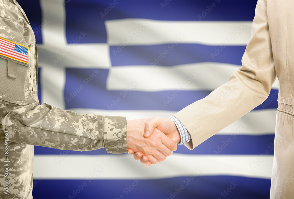 USA military man in uniform and civil man in suit shaking hands with adequate national flag on background - Greece