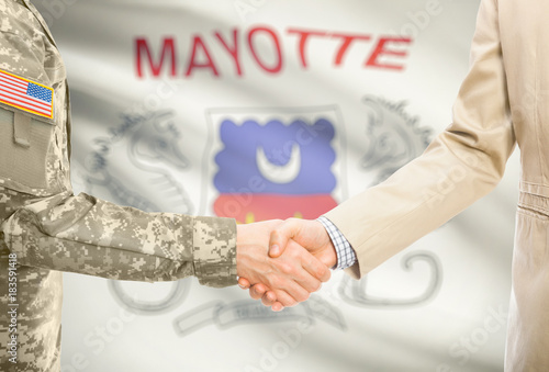 USA military man in uniform and civil man in suit shaking hands with adequate national flag on background - Mayotte photo