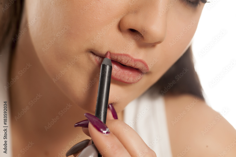young beautiful woman applyied lip pencil on her lips
