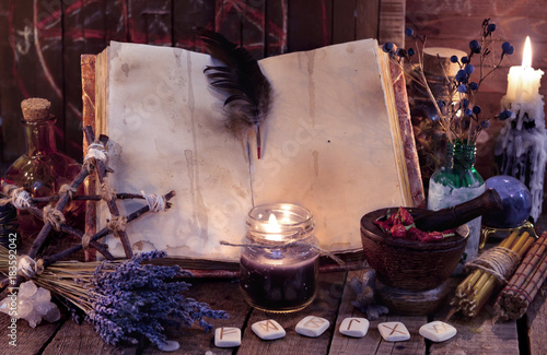 Witch book with pentagram, runes, magic objects and black candle. Occult, esoteric, divination and wicca concept. Mystic and vintage background