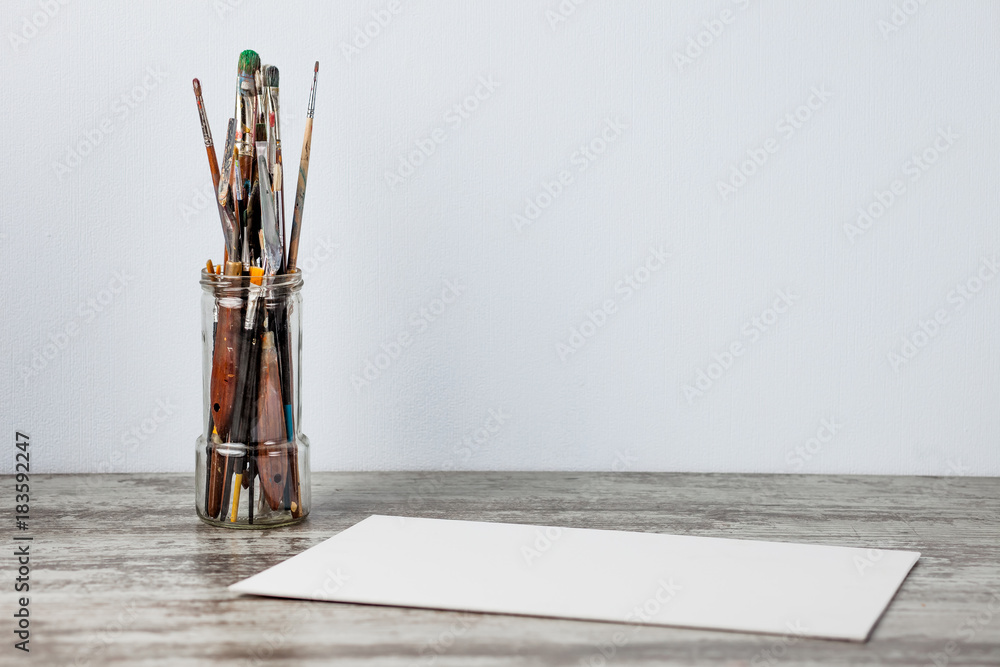 Paint brush in a glass, jar. Оn a light blue background. With copy space Paint brush in a glass, jar. Оn a light blue background. With copy space