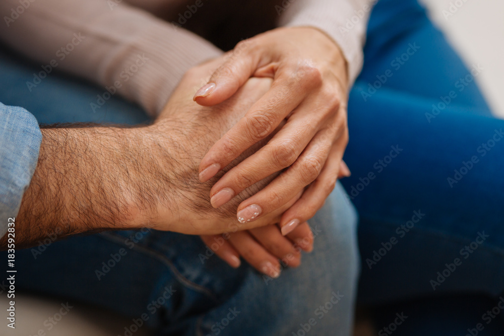 Love everywhere. Close up of young couples hands caught together placing them on the knees Love everywhere. Close up of young couples hands caught together placing them on the knees