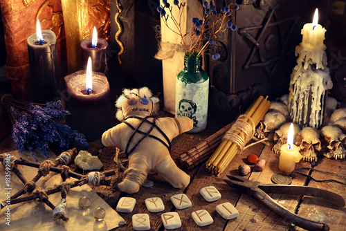Voodoo doll, black candles, pentagram and old books on witch table. Occult, esoteric, divination and wicca concept. Mystic, voodoo and vintage background