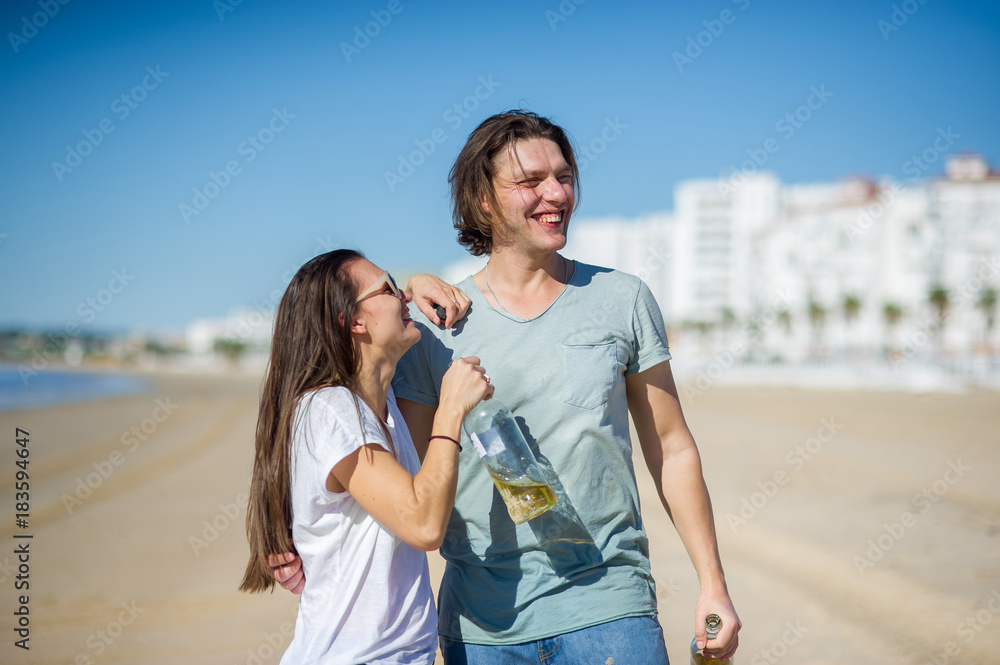 Cheerful young couple drinks wine on the beach. Cheerful young couple drinks wine on the beach.