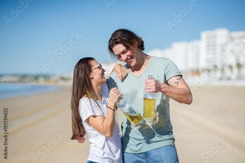 Cheerful young couple drinks wine on the beach.