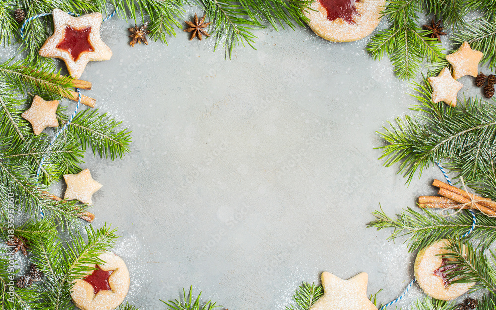Ginger homemade cookies with strawberry jam on gray concrete background with Christmas tree. Winter holidays concept. Flat lay, top view. Xmas Border - horizontal banner. Web size. 
