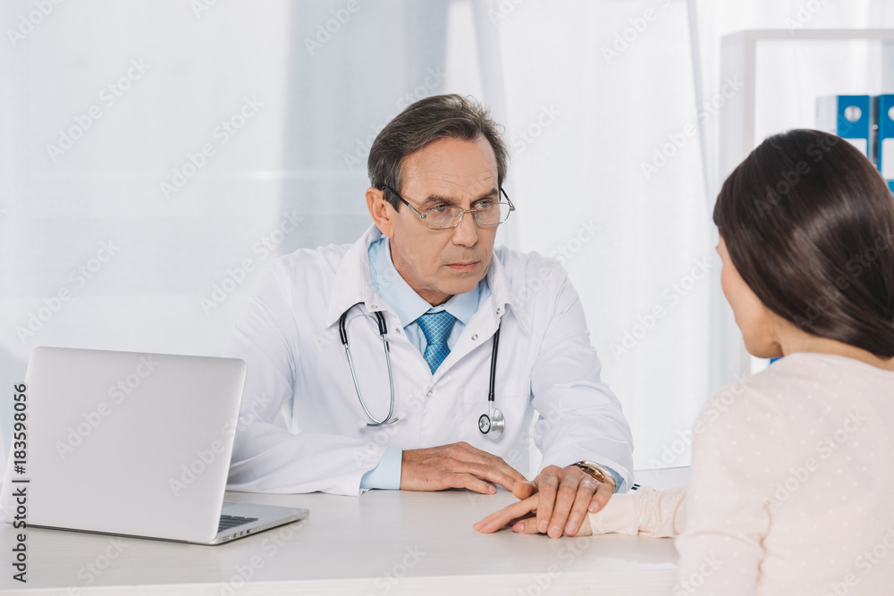 doctor and female patient holding hands at clinic doctor and female patient holding hands at clinic