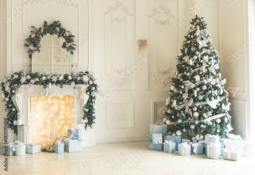 Christmas living room with a Christmas tree, fireplace, gifts and a large window. Beautiful New Year decorated classic home interior photo