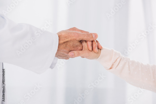 cropped image of male doctor holding female patient hand