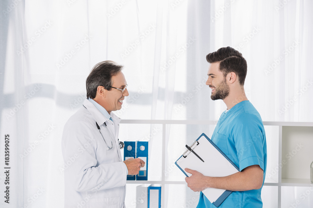 Fototapeta premium smiling doctor talking to nurse at clinic