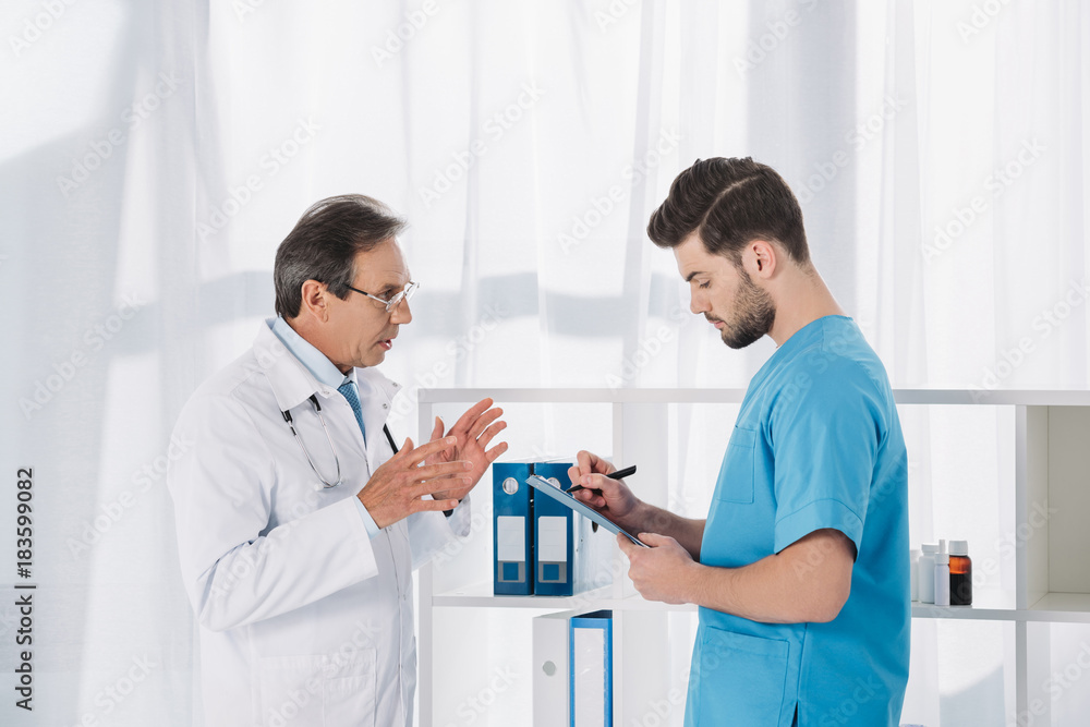 male nurse writing down something after doctor male nurse writing down something after doctor