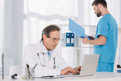 male doctor working at laptop in clinic