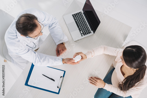 overhead view of doctor giving pills to female patient