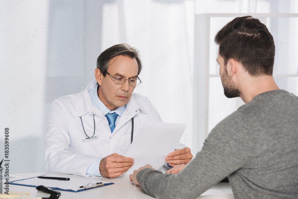 doctor reading male patient documents