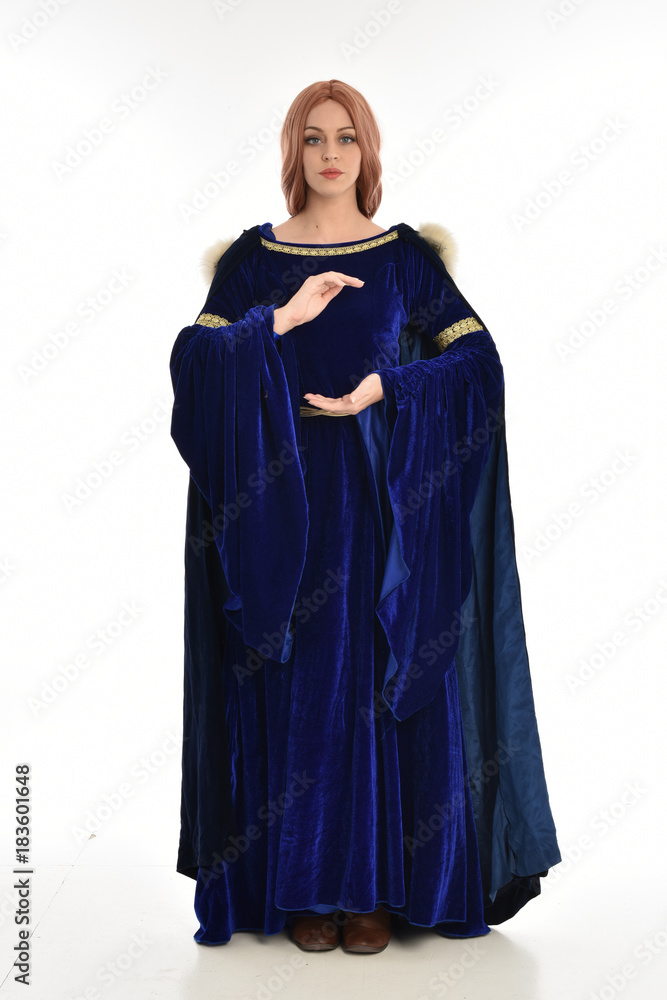 full length portrait of girl wearing long blue velvet gown and fur lined cloak, standing pose  on white background.