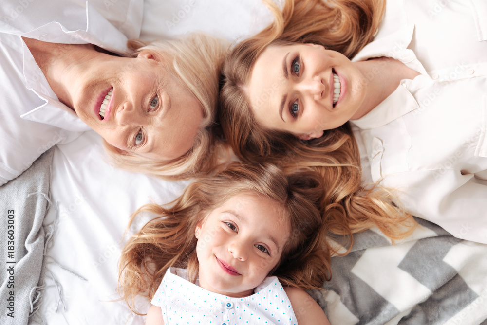 Family unity. Happy delighted positive family looking at you and smiling while lying together Family unity. Happy delighted positive family looking at you and smiling while lying together