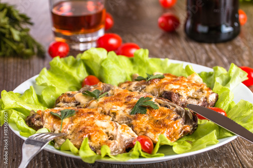 Baked meat with chopped onions and cheese on a salad leaf