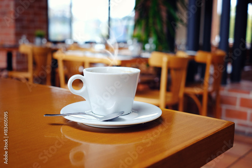 White cup of coffee over blurred cafe interior