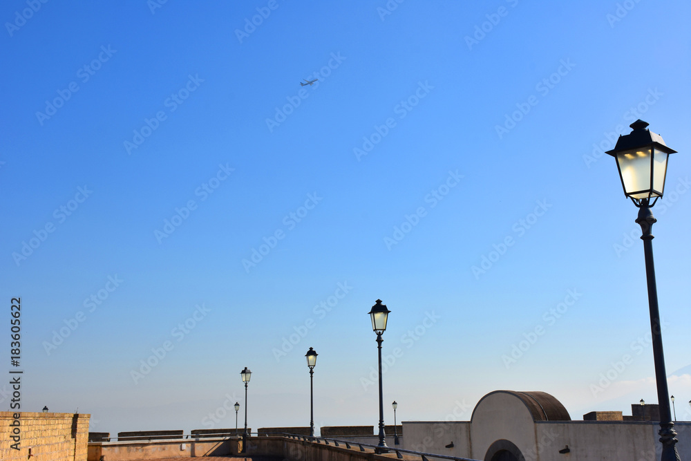 Napoli, Castel sant’Elmo. Castello medievale, 1329, in parte ricavato dalla viva roccia (tufo giallo napoletano); è il punto più alto della città. Lampioni con passaggio di aereo Napoli, Castel sant’Elmo. Castello medievale, 1329, in parte ricavato dalla viva roccia (tufo giallo napoletano); è il punto più alto della città. Lampioni con passaggio di aereo