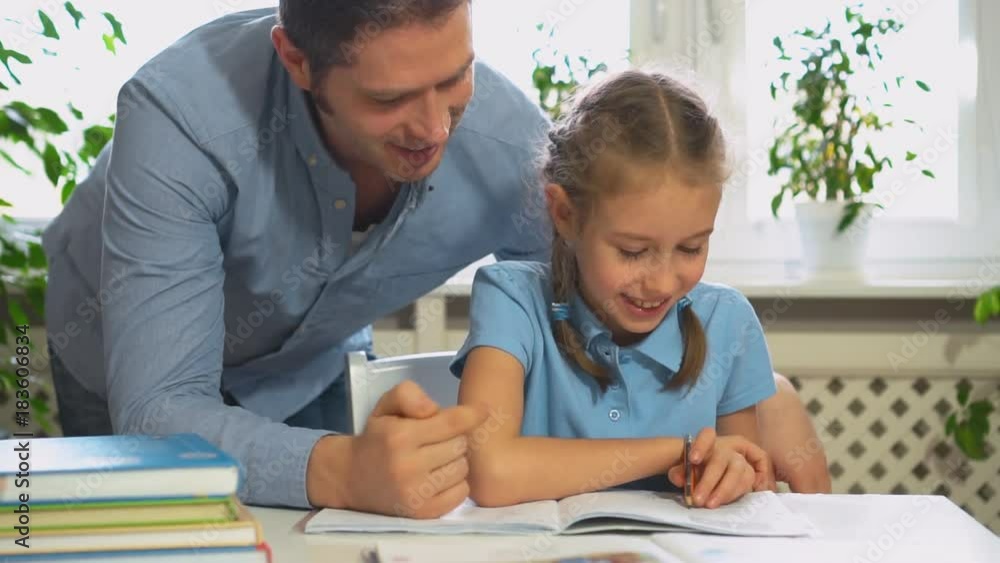 Father helping daughter with homework at home. Father helping daughter with homework at home.
