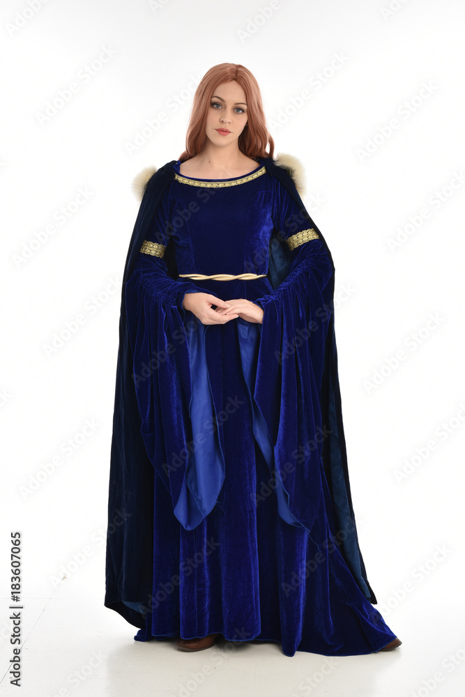 full length portrait of girl wearing long blue velvet gown and fur lined cloak, standing pose  on white background.