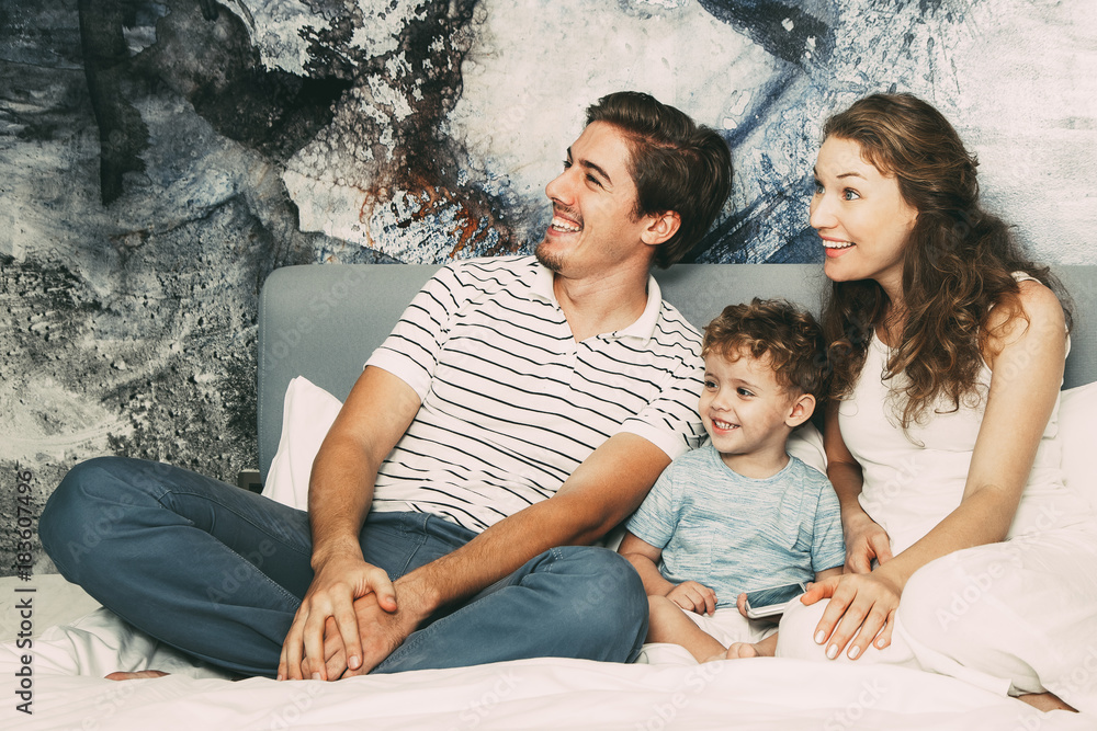 Happy family with son sitting together on bed Happy family with son sitting together on bed
