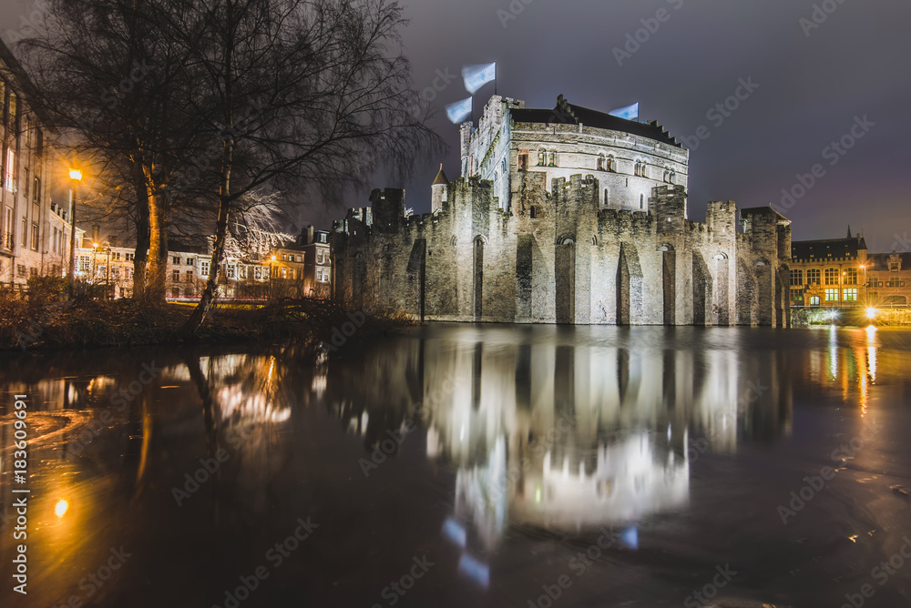Night Gravensteen  view - historical medieval castle on water in Ghent, Flanders, Belgium. Castle of Counts stronghold reflected on canal in Gent city by evening illumination.