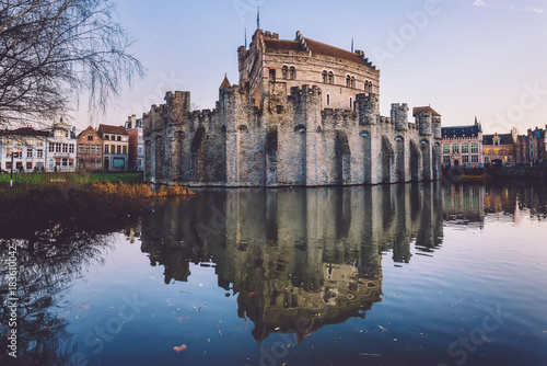 Gravensteen - historical medieval castle on water in Ghent, Flanders, Belgium. Castle of Counts stronghold reflected on canal in Gent city by sunset.