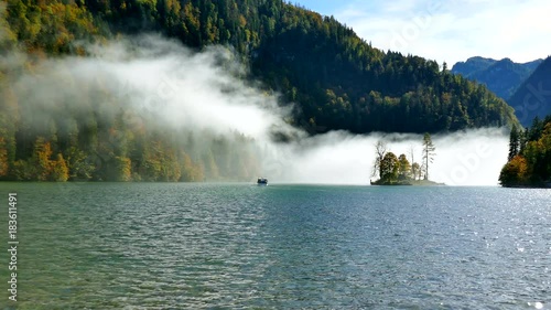 Mystic and beautiful isle with foggy clouds at lake Knigsee in Bavaria, Germany with vessel shipping people to the St. Bartholomew's Church in Berchtesgaden near mountain Watzmann  photo