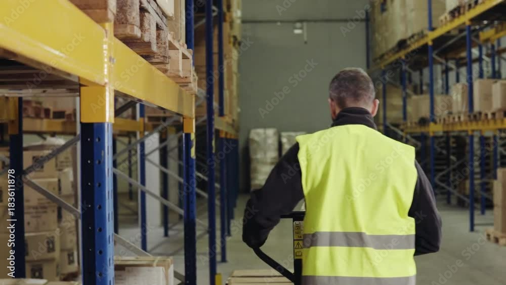 Male warehouse worker unloading boxes from pallet truck. Male warehouse worker unloading boxes from pallet truck.