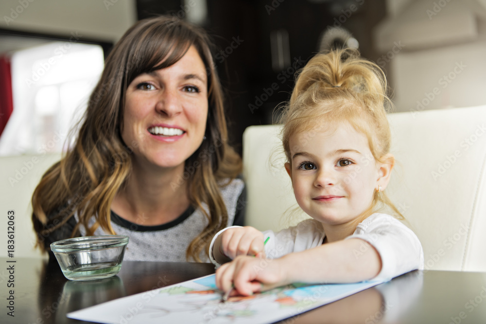Mother and daughter painting together at home with paintbrushes and watercolors Mother and daughter painting together at home with paintbrushes and watercolors