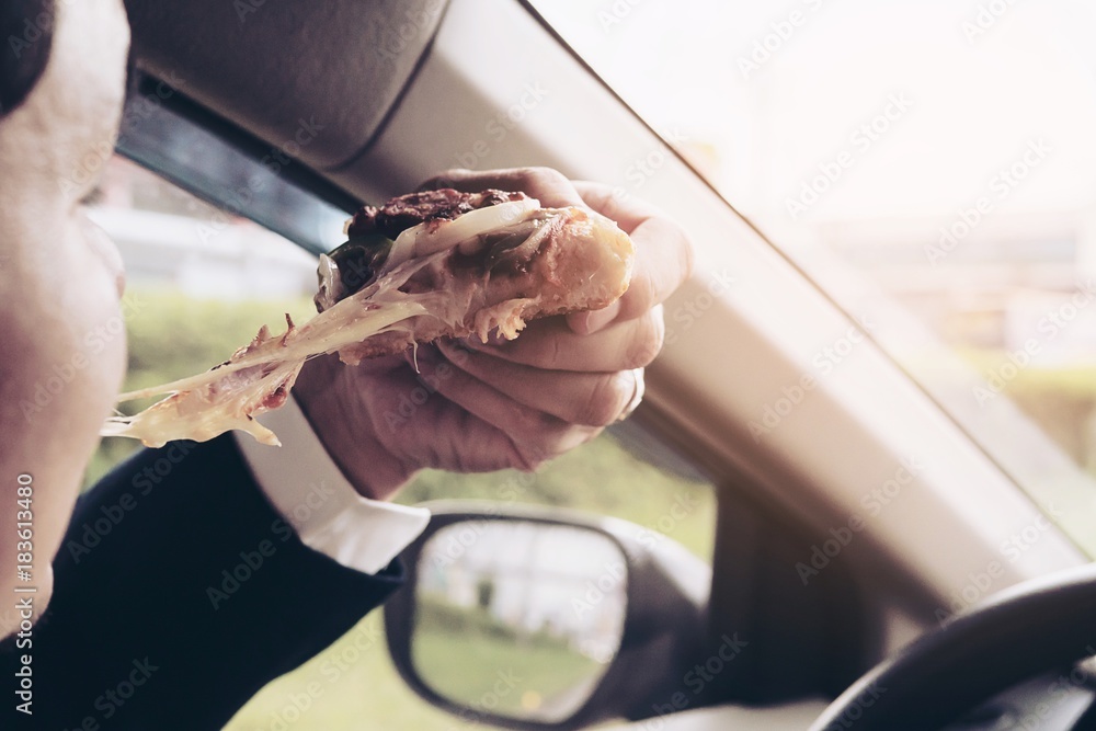 Man eating pizza and coffee while driving car dangerously