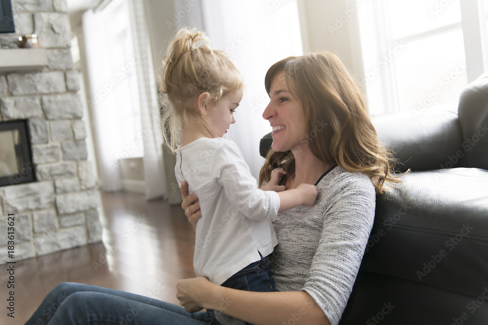 Happy mother with her baby daughter in the living room at home