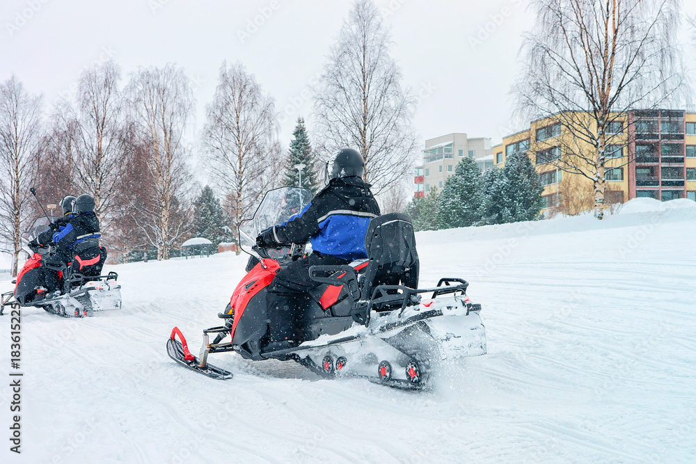 People riding snowmobiles on frozen lake in winter Rovaniemi