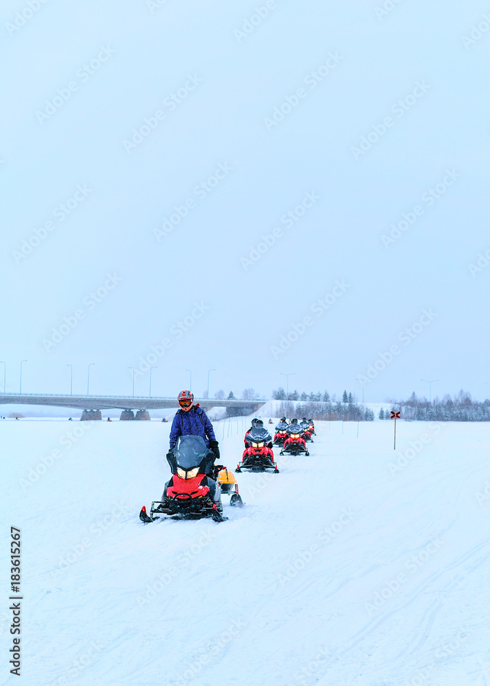 Peopla riding snowmobiles on frozen lake at winter Rovaniemi
