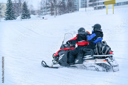 People riding snowmobile in frozen snow lake in winter Rovaniemi