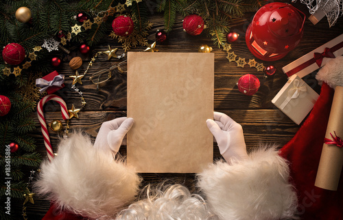 Close up of Santa Claus hands holding, reading blank letter with copy space