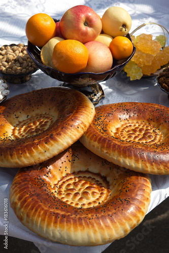 Traditional Uzbek bread,fruit in a vase and sweets on the table.