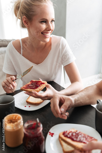 Smiling blonde woman talking and put jam on bread