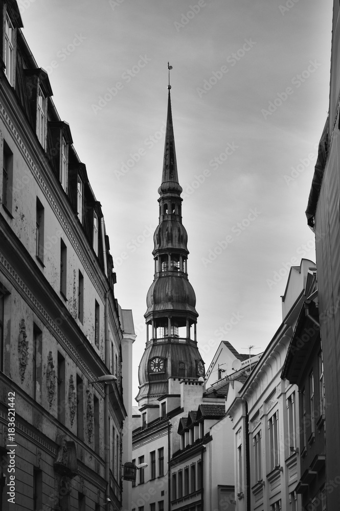 Symbol of Riga, old clock on medieval church tower (St. Peter's Church in Old Town Riga) among ancient buildings of narrow European street