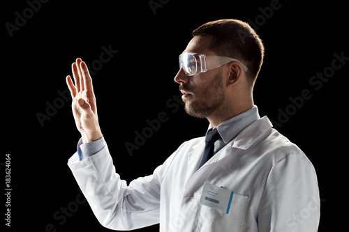 doctor or scientist in lab coat and safety glasses