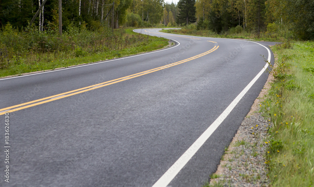 Curvy asphalt road on autumn day in Finland. Yellow lines and clean road. Highway to drive. Curvy asphalt road on autumn day in Finland. Yellow lines and clean road. Highway to drive.