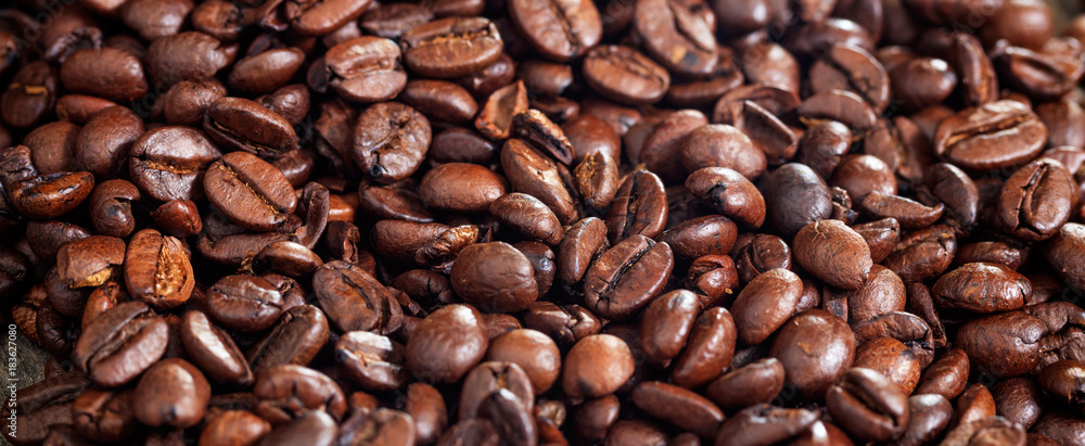 Naklejka premium Roasted coffee beans background. Closeup view and details.
