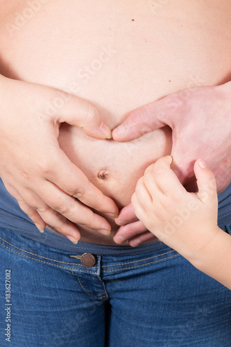 pregnant woman and husband hands hugging the tummy with kid