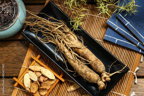 Fotografía .ginseng in black plate on wooden table