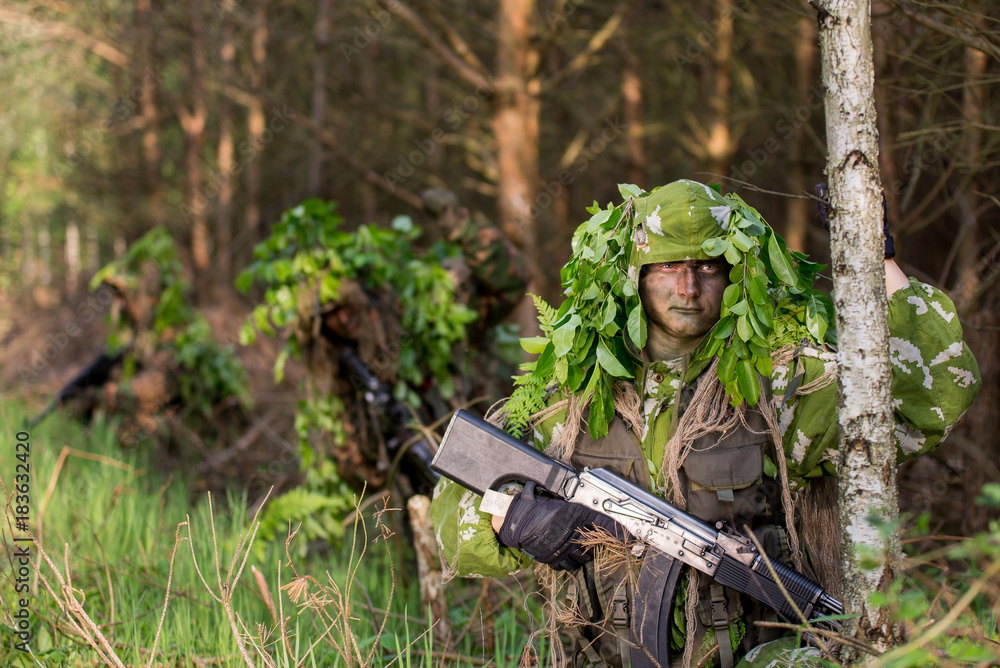 Naklejka premium Camouflaged soldiers in forest during early spring on patrol