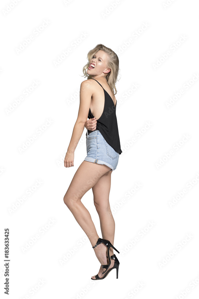Fototapeta premium Blonde junge Frau in kurzen hot pans schaut über die Schulter und steckt die Zunge heraus